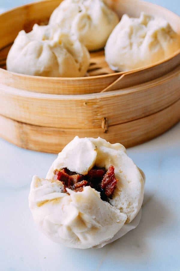 A picture of four char siu baos. One is broken open.